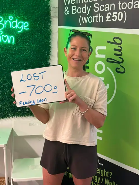 Inside the club, a member displays her assessment results on a whiteboard