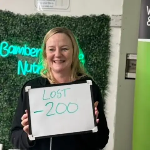 Inside the club, a member displays her assessment results on a whiteboard